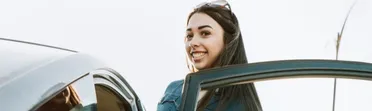 Smiling woman beside an open car door after a SafeTrade purchase